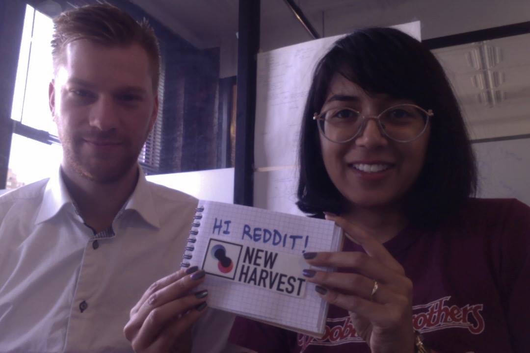 Dan and Isha holding up a sign that says 'Hi Reddit!' above the New Harvest logo