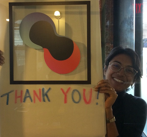 Isha holding up a sign that says "thank you"